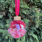 Decorative Christmas ornament with pink and purple confetti on a tree